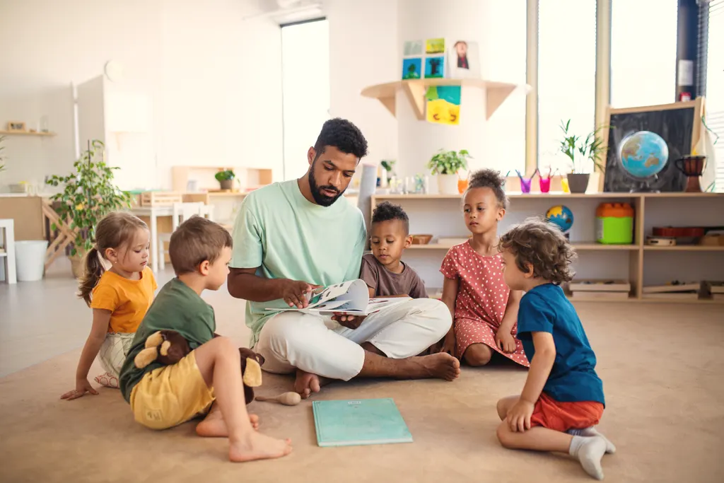 A practitioner sits cross-legged reading a story to a small group of children
